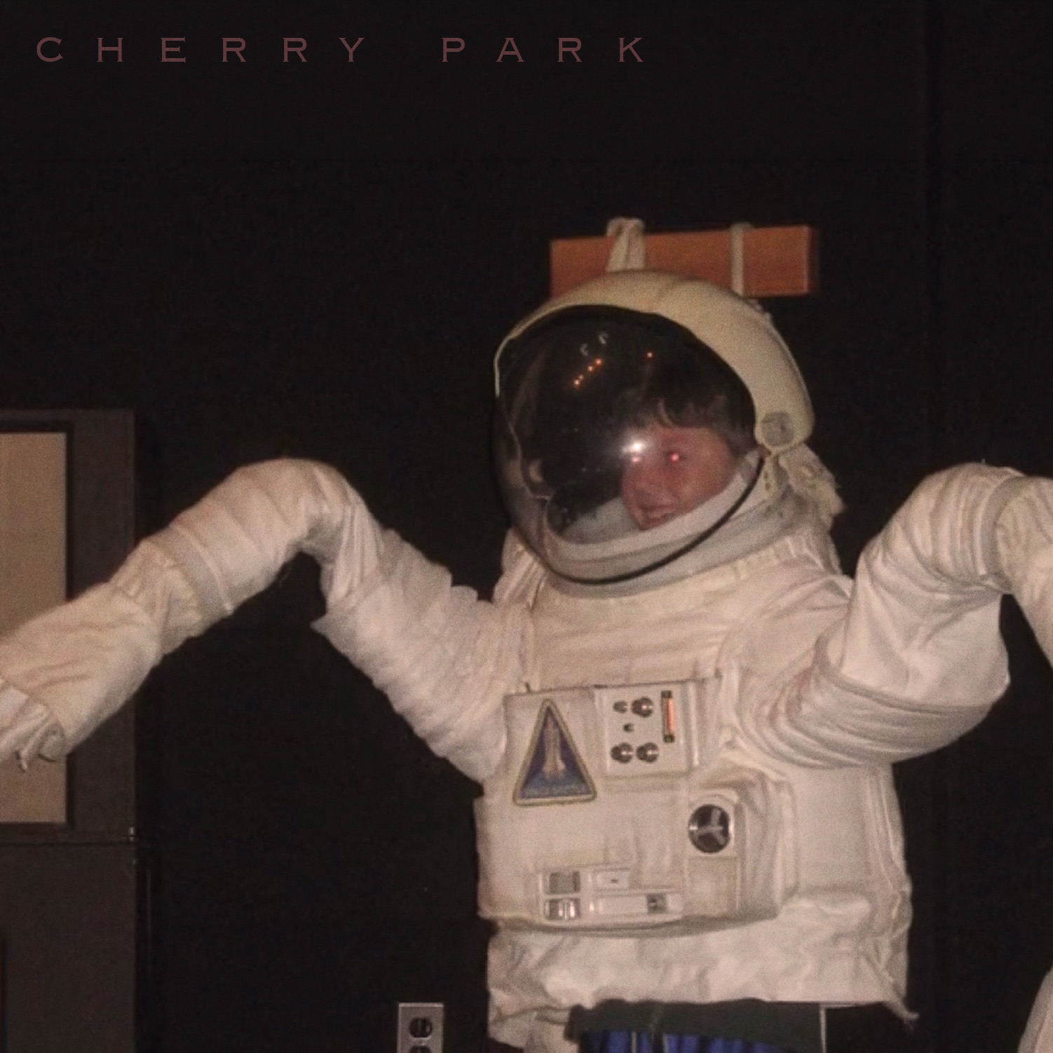 A young child in a space suit with arms raised in a silly pose for the Cherry Park EP, Volume #1